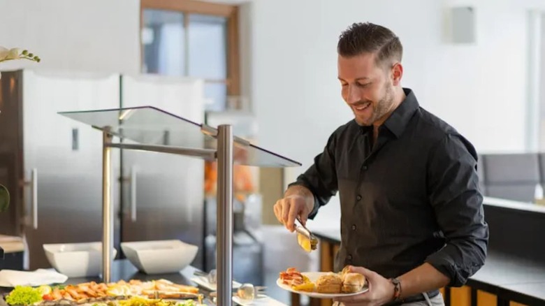 Man putting food on his plate at a buffet