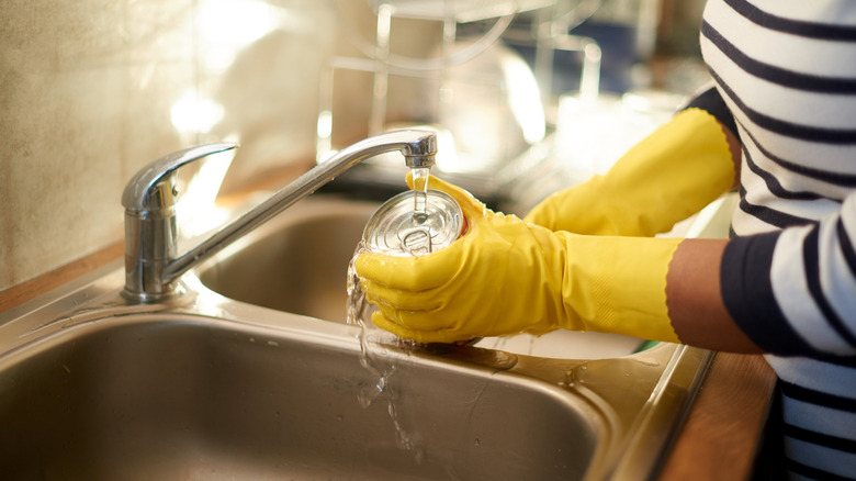 women cleaning can in sink