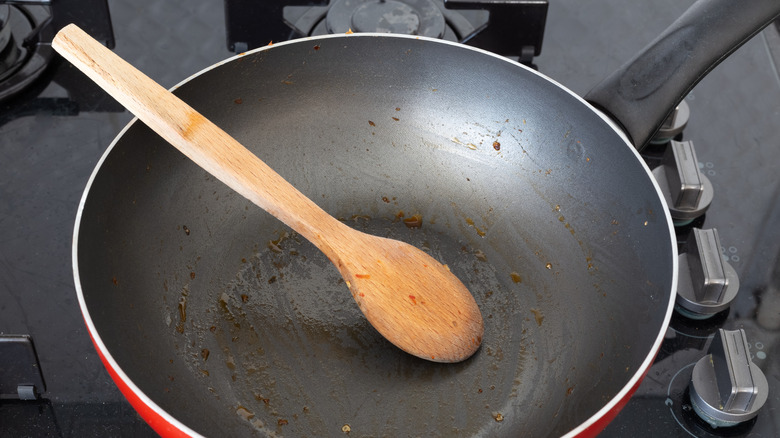 A wooden spoon in a pan with grease remnants