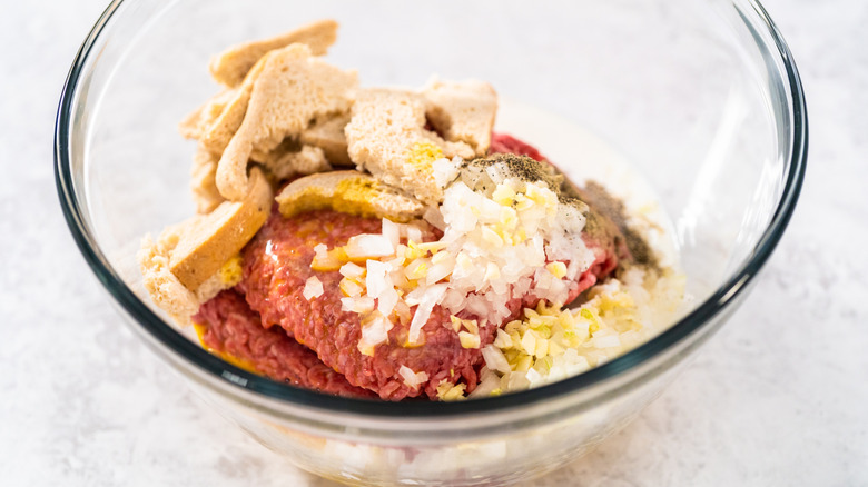 Meatloaf ingredients, unmixed, in a glass bowl