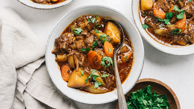 A bowl of beef stew sitting on a table.