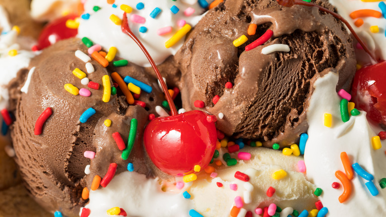 A close up shot of a chocolate and vanilla ice cream sundae with a maraschino cherry