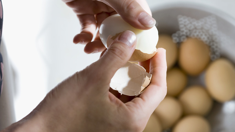 hands peeling boiled eggs