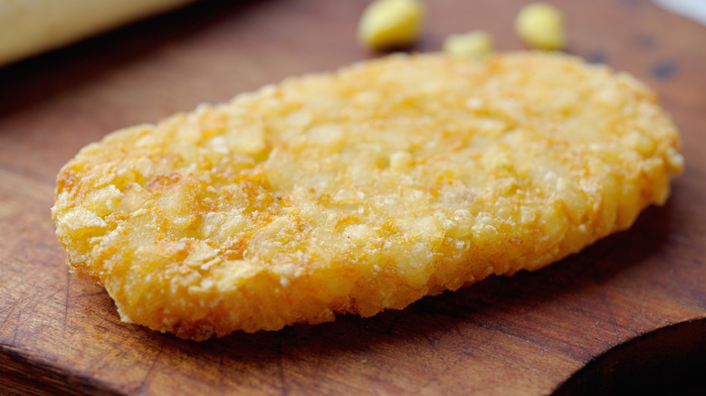 A golden and crispy hash brown sitting on a cutting board.