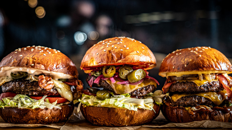 Three burgers with various different toppings next to one another.