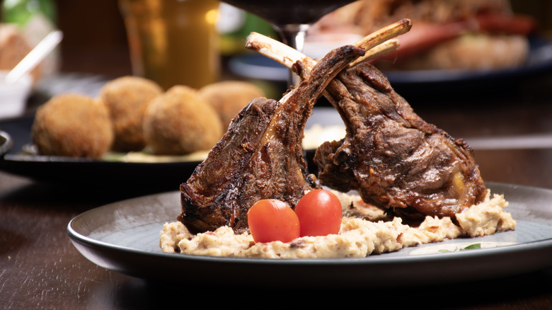 A lamb dish with appetizers behind it at a steakhouse