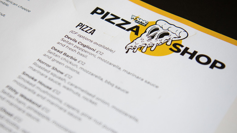 A pizza menu with a cartoon logo of a skull-eyed pizza slice