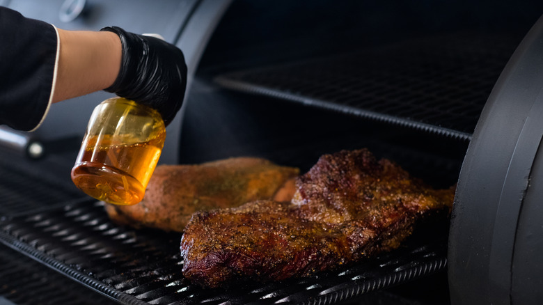 Spraying brisket on a smoker