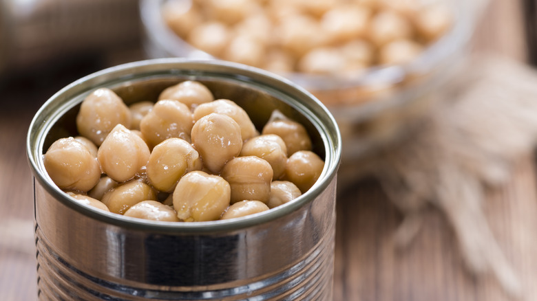 open can of chickpeas with bowl of chickpeas in background