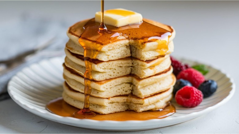 Fluffy pancakes in a stack with a square of butter on top and syrup