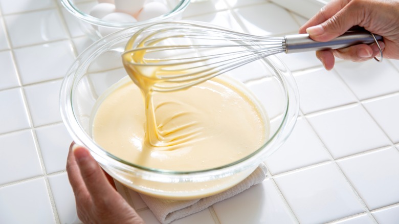 A bowl of pancake batter and a whisk