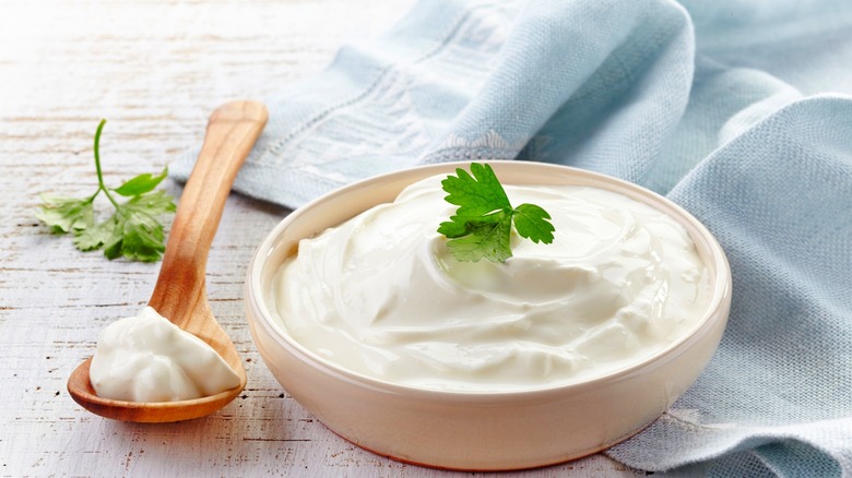 A bowl of sour cream and a wooden spoon