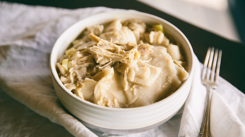 Chicken and dumplings served in a white bowl on a napkin