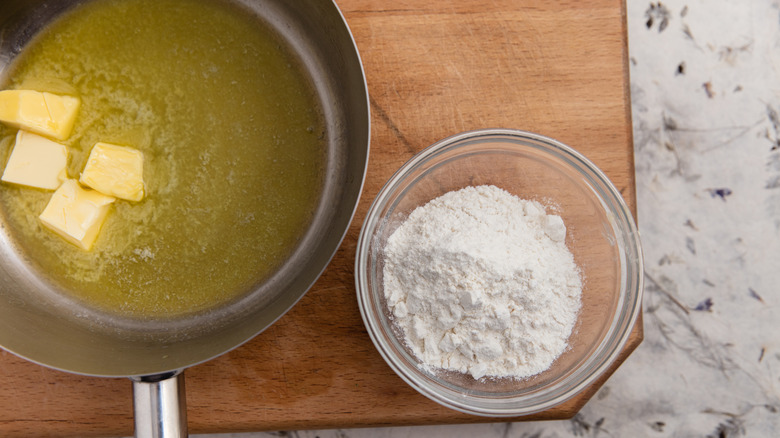 Butter melting in a skillet next to a bowl of flour