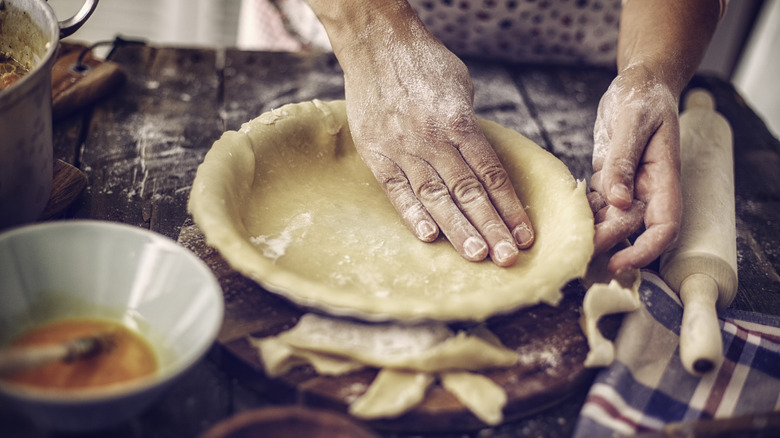 Person preparing bottom crust for pot pie