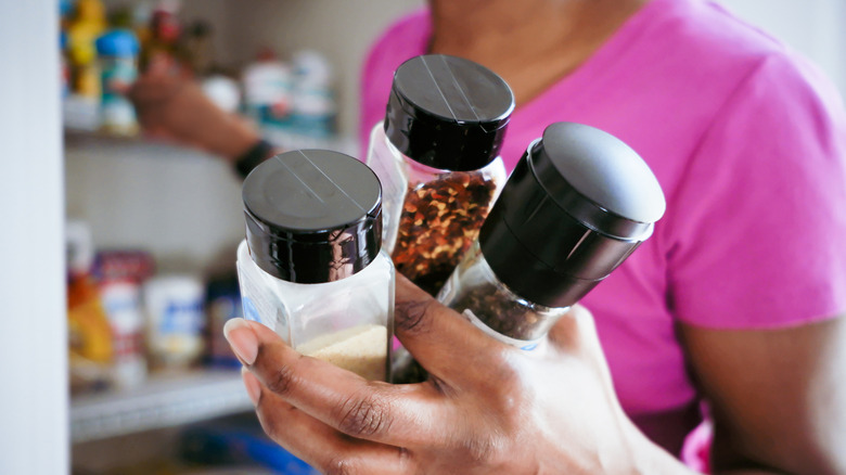 Person holding different seasoning jars in one hand