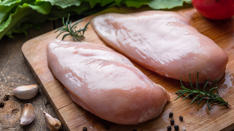 Raw chicken breasts on a wooden cutting board