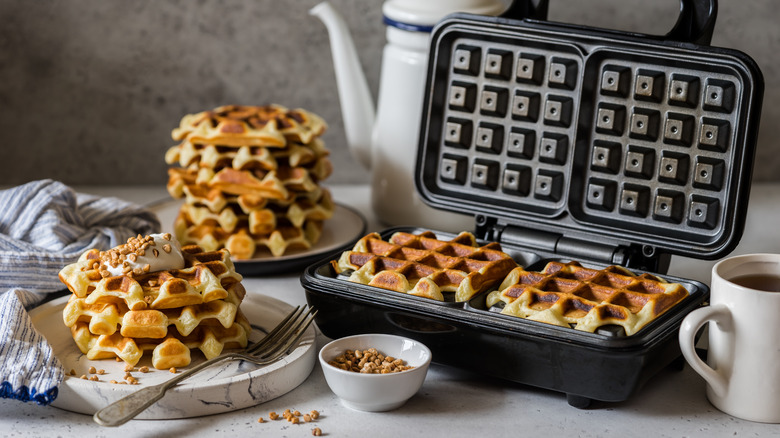 waffles being made in waffle iron served on plate with cream