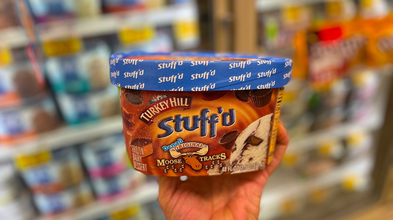 Hand holding tub of Moose Tracks ice cream in grocery store