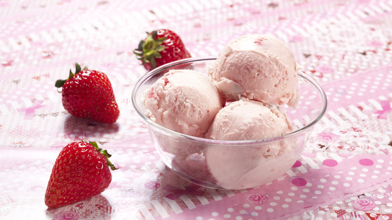 Strawberry ice cream scoops in clear bowl