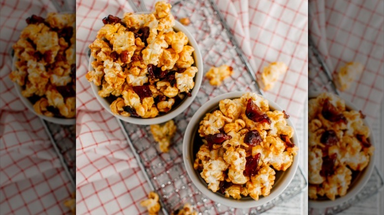 two cups of popcorn with bacon bits on a red and white checked dishtowel