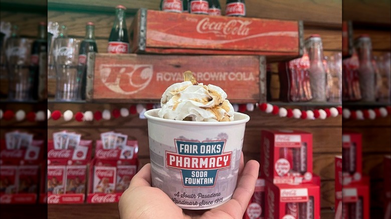 Fair Oaks Pharmacy with person holding ice cream in front of Coca-Cola paraphernalia