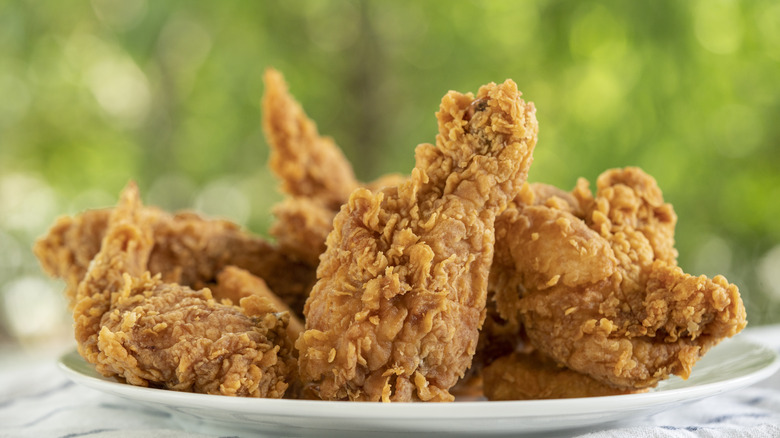 Several pieces of fried chicken stacked on a plate.