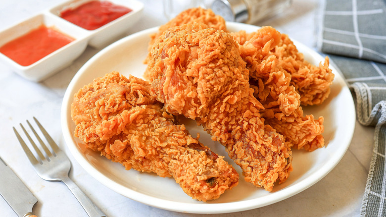 Four pieces of fried chicken on a plate next to two sauces.