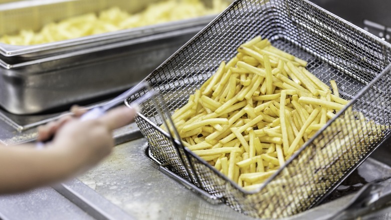 Fast food fries in a fry basket about to be fried