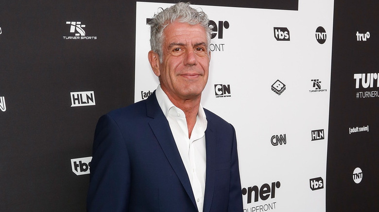 Anthony Bourdain wearing navy blue suit and white shirt at an event.