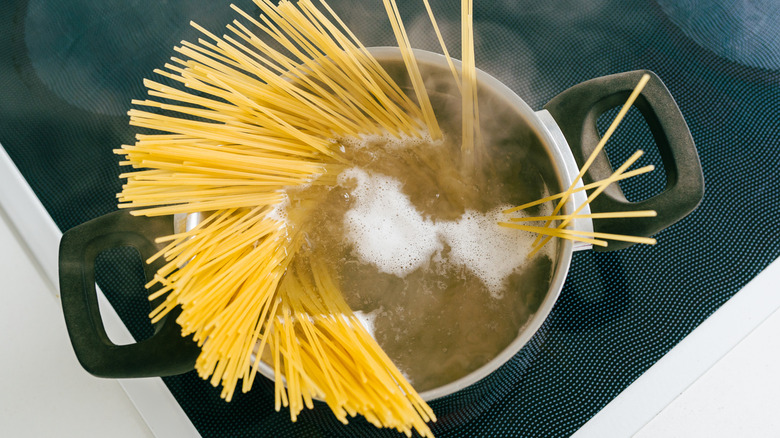 Raw uncooked pasta boiling in a cooking dish on a stove