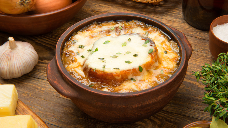 A hearty bowl of French onion soup in a bowl with a baguette in the middle