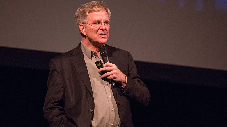 TV personality Rick Steves on stage with a microphone in his hand