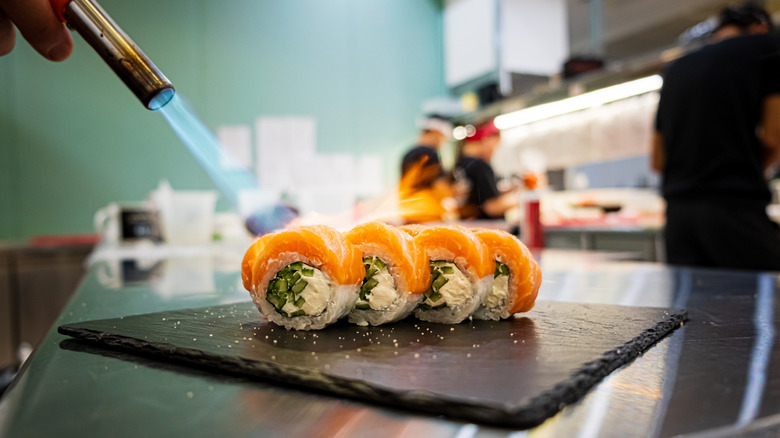 Searing the fish on a sushi roll with a kitchen torch