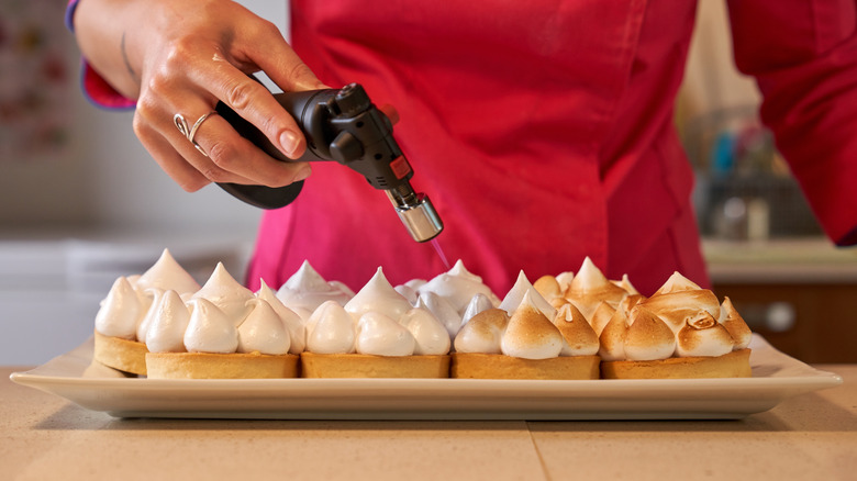 Person torching meringues on a platter