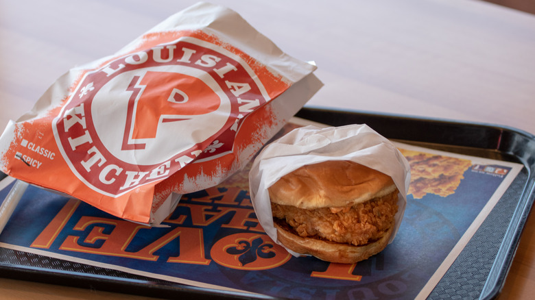 Popeyes chicken sandwich and food bag on tray