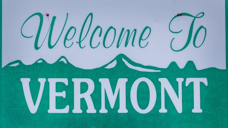 A close up of a green and white road sign that reads "Welcome To Vermont"