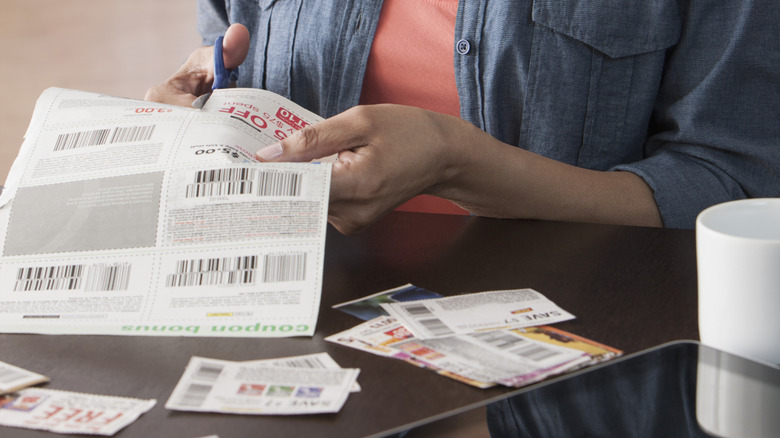 A woman cuts coupons at the kitchen table