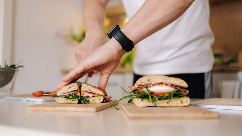 A person cutting a sandwich in half.