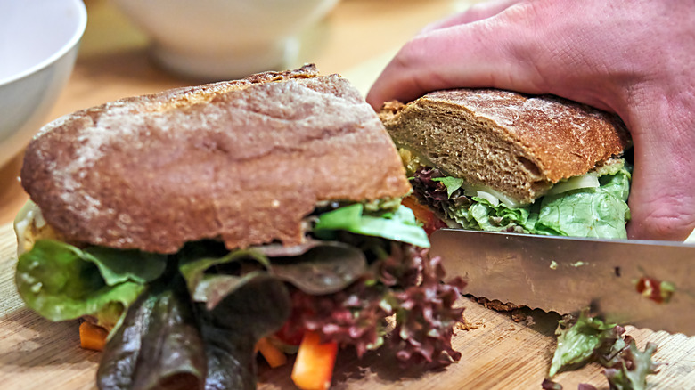 A person cutting a sandwich.