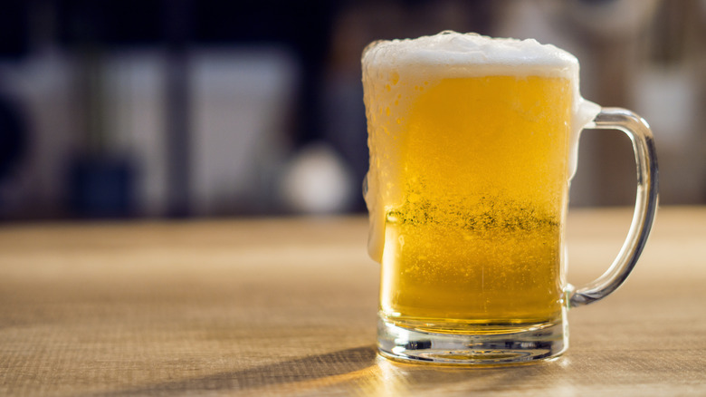 Cold mug of light beer sitting on a surface