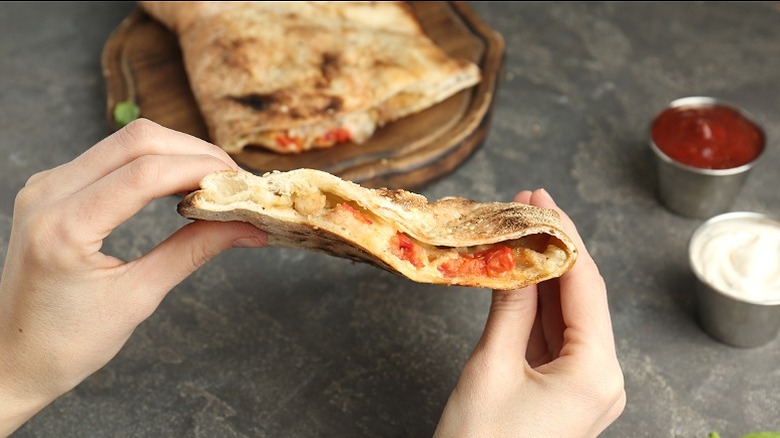 A person eating a calzone by hand.