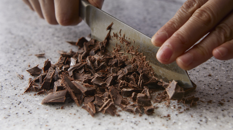 Chopping chocolate with a knife on a stone surface