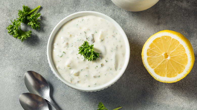 Tartar sauce in a bowl with fresh herbs and lemon