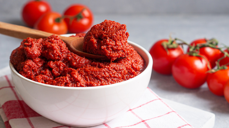 Tomato paste in a bowl with a wooden spoon