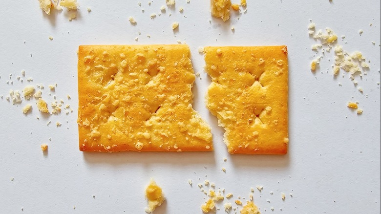 rectangle cracker broke in half with its crumbs scattered