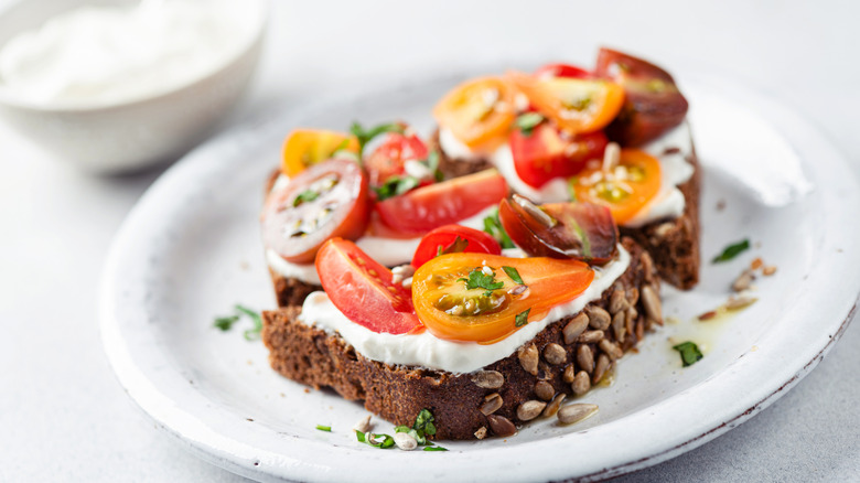 An open-faced tomato and mayo sandwich on whole grain bread