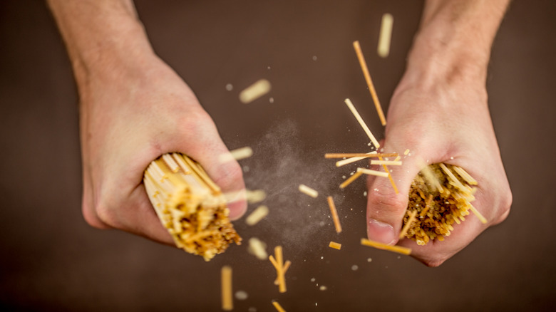 hands snapping dry spaghetti noodles in half