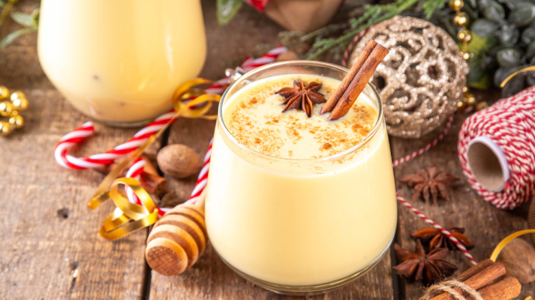 A glass of eggnog with cinnamon stick and cinnamon sprinkled on top