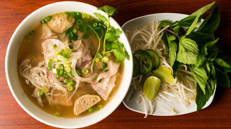 A bowl of pho sitting on a table.